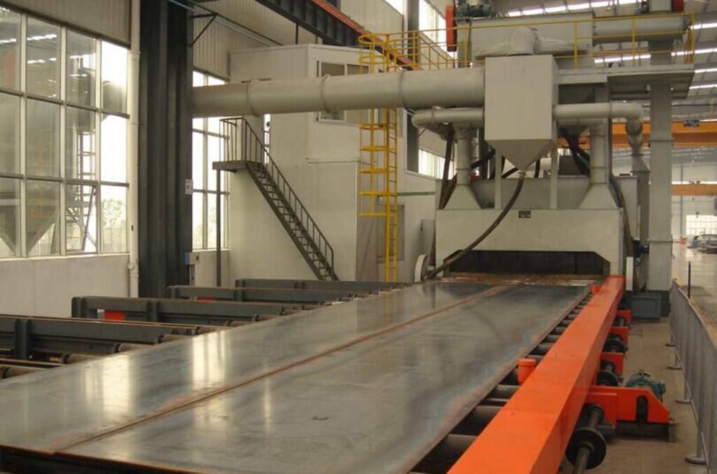 Continuous Pass Through Shot Blasting Machine is an automatic abrasive blasting system designed to continuously transport steel plates or other metal workpieces through an enclosed blasting chamber.