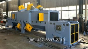 wire mesh belt shot blasting machine is a continuous pass-through type surface treatment equipment. It uses a stainless-steel wire mesh conveyor belt to transport workpieces steadily through a blasting chamber, where high-speed blast turbines throw steel shots onto the surface for cleaning, descaling, deburring, and surface strengthening.
